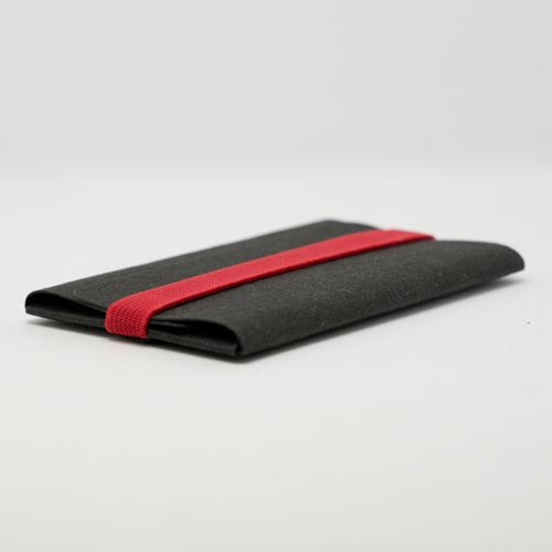 extrem dünnes Kartenetui in Schwarz mit rotem Gummiband flach vor einem grauen Hintergrund liegend