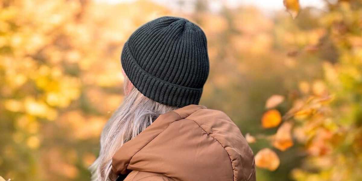 Gemütlicher warmer Herbstspaziergang – Frau mit Merino-Mütze in warmen Farben.